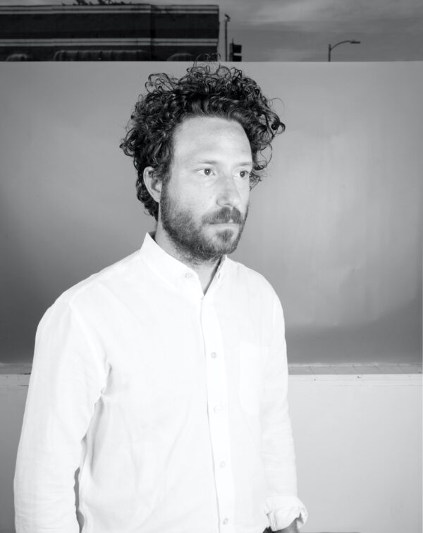 Black and white portrait of a man with curly hair and a beard looking off to the right