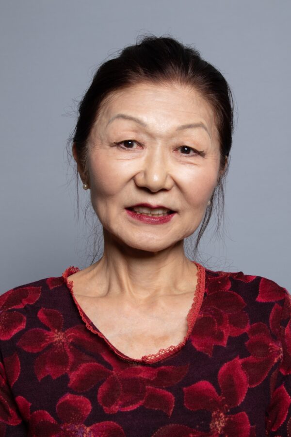 Portrait of a woman with black hair pulled back against a grey screen