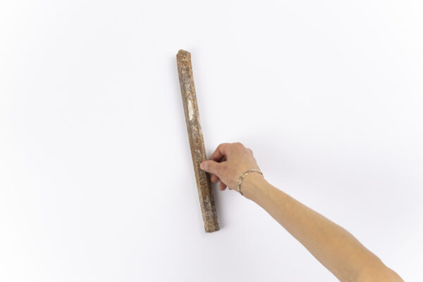 A right hand holds a rusty bar against a white background