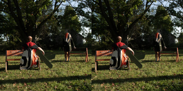 A stereograph depicting people in a park setting in late afternoon. One person sits on a bench, their back to the viewer, while another person stands near a similar bench with a bandana over their head.