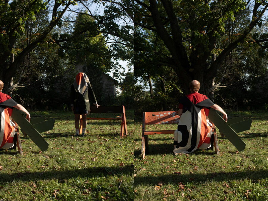 A stereograph depicting people in a park setting in late afternoon. One person sits on a bench, their back to the viewer, while another person stands near a similar bench with a bandana over their head.