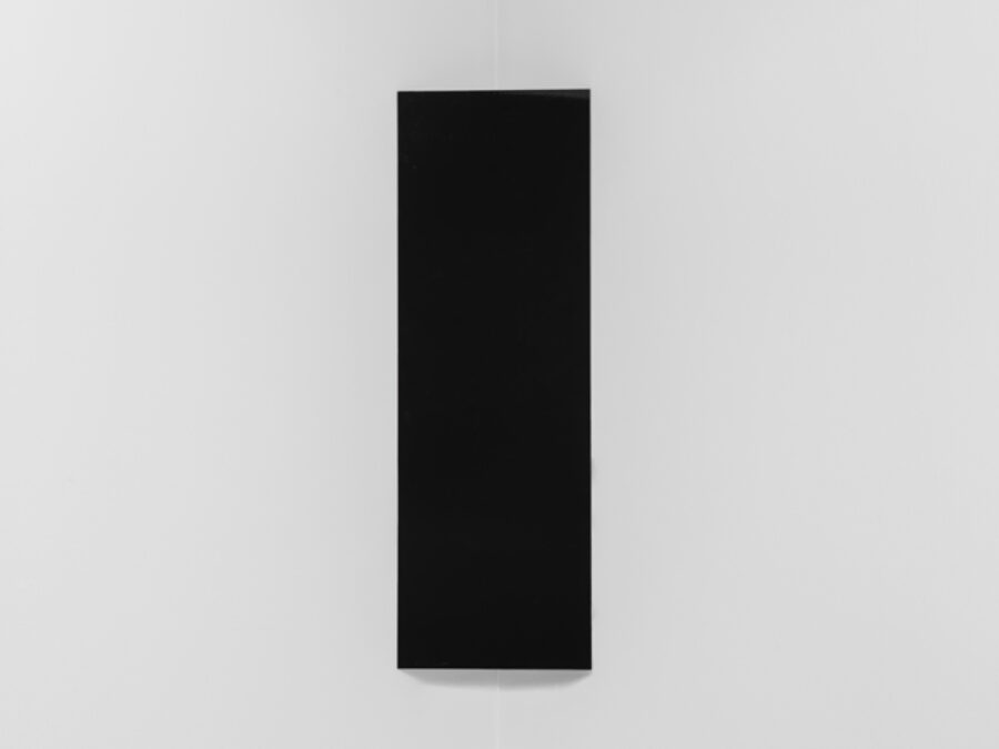 A stark black rectangle hung vertically in the corner of a white-walled room.
