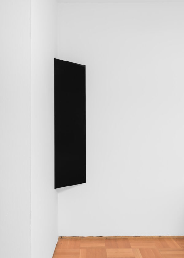 A stark black rectangle hung vertically in the corner of a white-walled room.