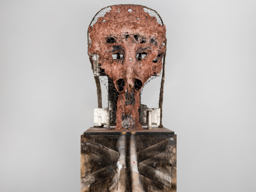 A sculpture resembling a human with head-like object on top of a vertical box that has been painted black and white