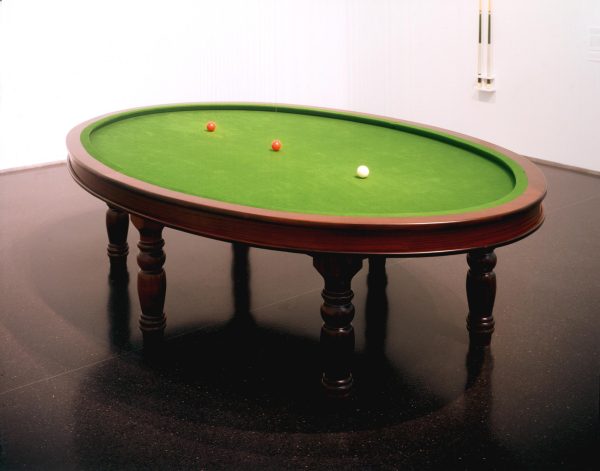 An oval pool table with three billiard balls sitting in a line on the surface