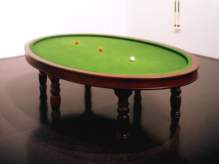 An oval pool table with three billiard balls sitting in a line on the surface