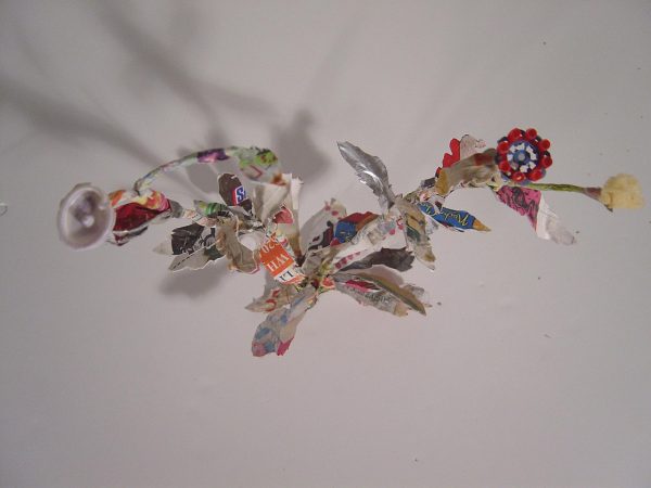 Colorful paper and objects are bound together and hung from a ceiling