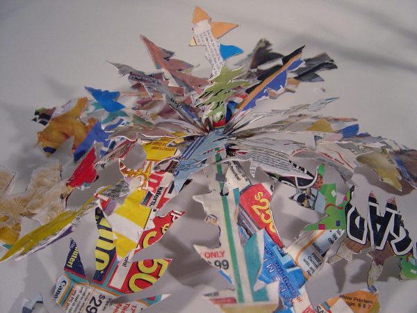 A sculpture in the shape of a plant is made out of various colorful newspaper ads.
