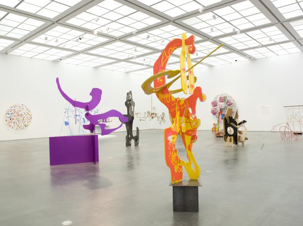 Interior of a modern art gallery displaying various colorful and abstract sculptures and paintings.