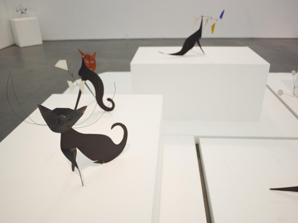 Exhibit of abstract cat sculptures by artist Alexander Calder, displayed on white pedestals in a gallery setting.