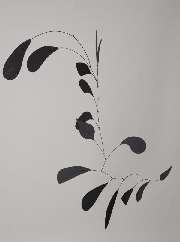 A black mobile made of wire and metal is suspended in air. The tips of the wire are adorned with leaf-like appendages.
