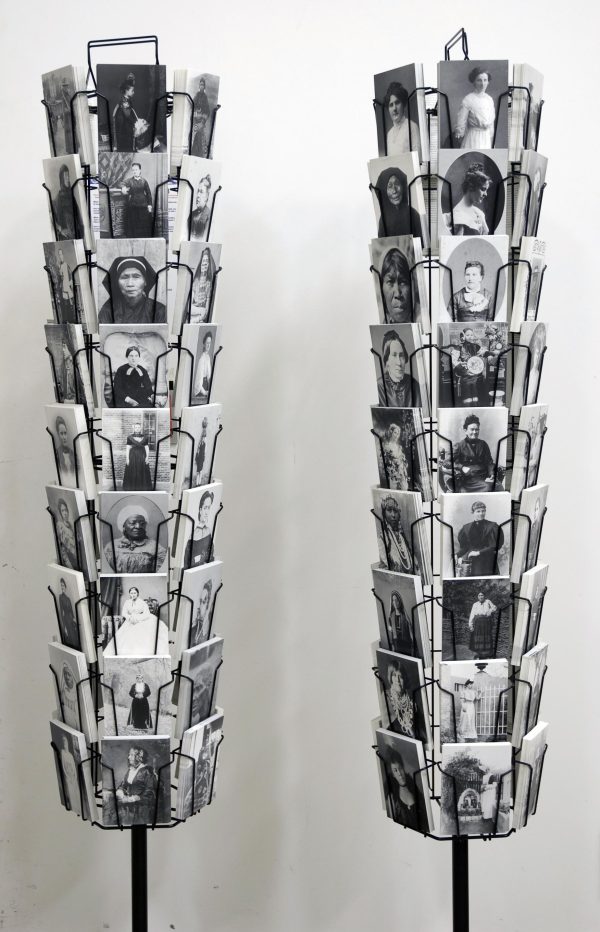 Two rotating postcard display racks hold various black-and-white portraits.