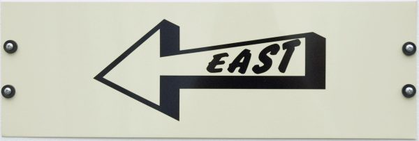 A white sign shows a black outline of an arrow pointing to the left. Inside the arrow in black text 