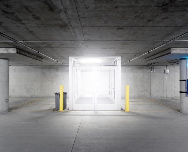 A bright white light glows from inside a cube in an underground parking garage