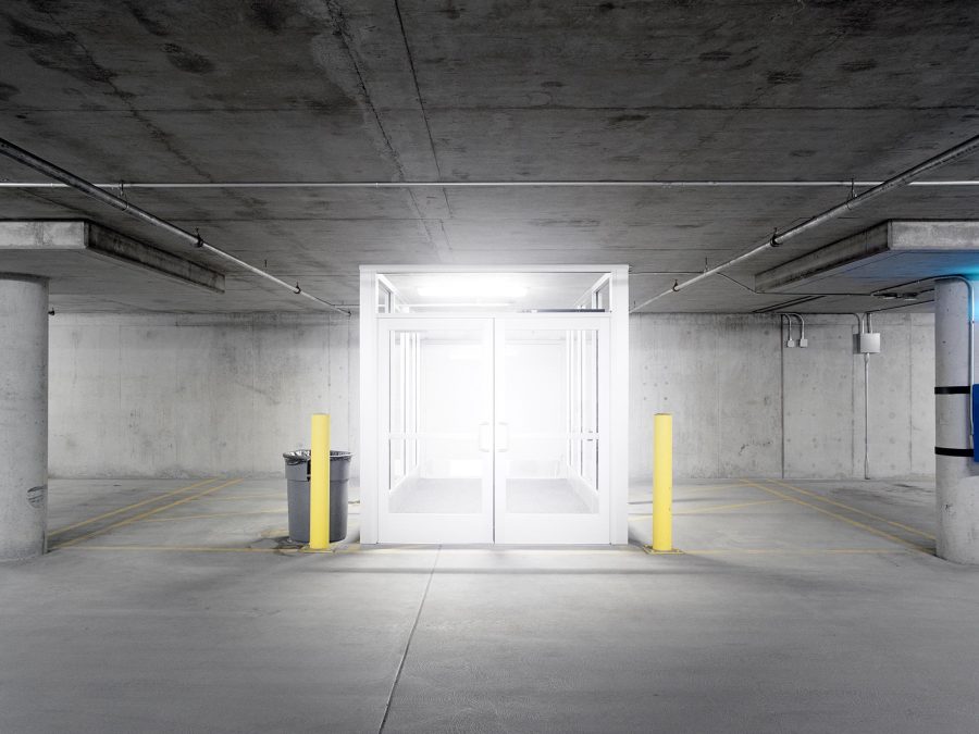 A bright white light glows from inside a cube in an underground parking garage