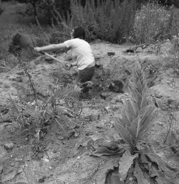 Black and white image of a person digging in the desert