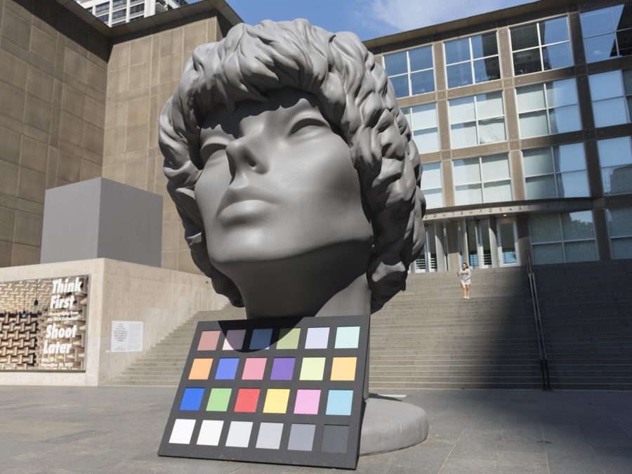 A huge sculpture of person's head is displayed along with a color palette in front of the MCA.