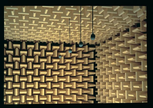 The upper corner of a sound studio with a row of four microphones hanging from the ceiling
