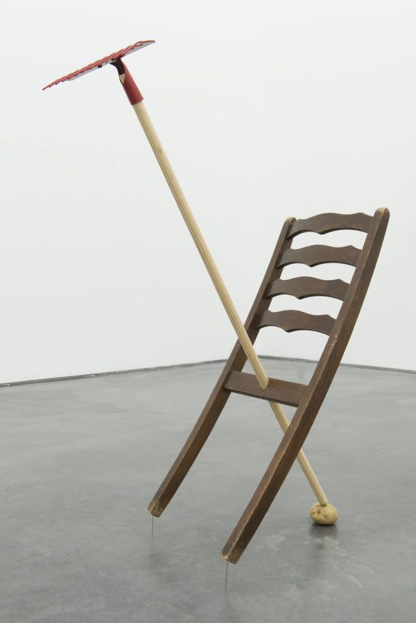 The back portion of a slatted dinner chair has been fused with a garden hoe, forming an 