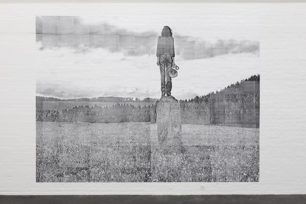 Black and white illustration on a white wall depicting a person standing on a plinth facing an indecipherable landscape