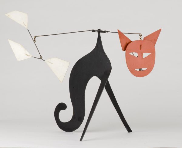 A mobile sculpture resembles a black cat with a red face.