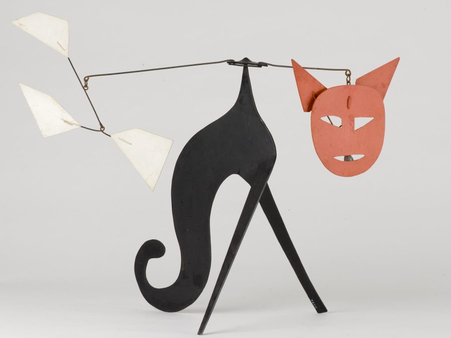 A mobile sculpture resembles a black cat with a red face.