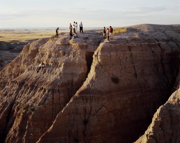 Twelve people stand on the top of a steep rock formation.