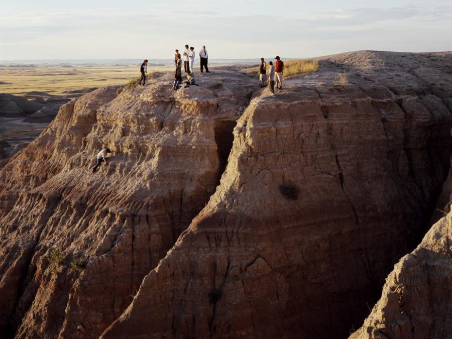 Twelve people stand on the top of a steep rock formation.