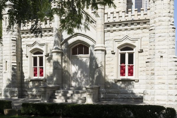 Close up view of Chicago's Water Tower. Red balloons inside the building are piled halfway up the two windows on either side of the double door.
