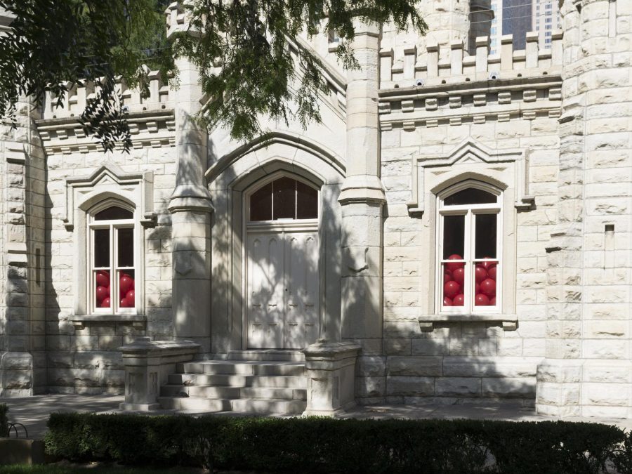 Close up view of Chicago's Water Tower. Red balloons inside the building are piled halfway up the two windows on either side of the double door.
