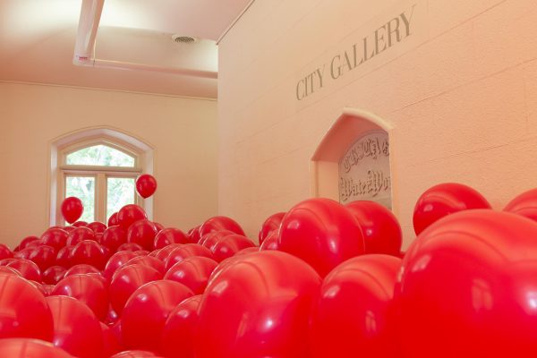 Red balloons cover the floor up to have the windows and doors in a room