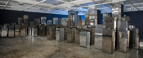 A room is filled with many fridges of various sizes, each covered entirely by small mirrors.