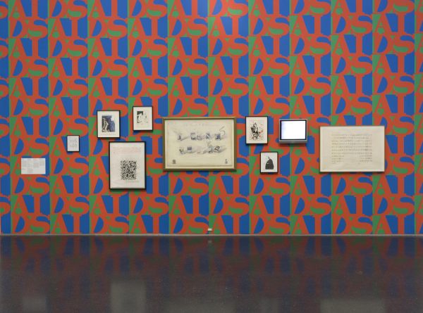 Artworks of varying sizes hung on a wall featuring AIDS patterned wallpaper