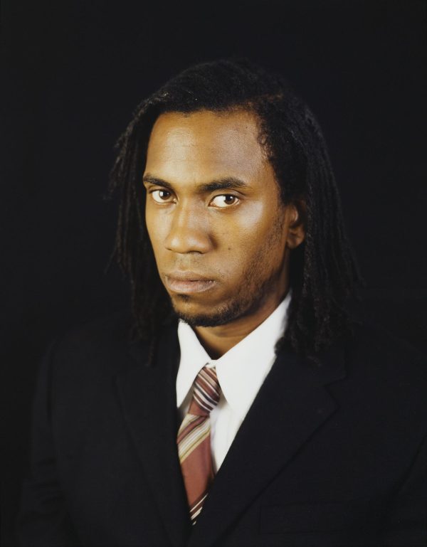 Three-quarter portrait of Rashid Johnson in a suit and tie looking confidently into the camera
