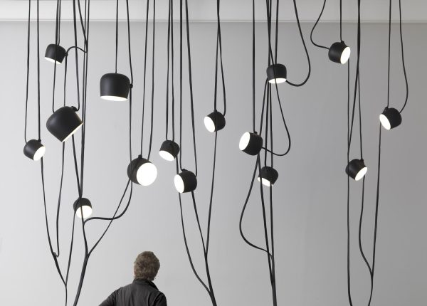 Black and white image of a person standing under several lights hanging in the middle of ropes at different heights