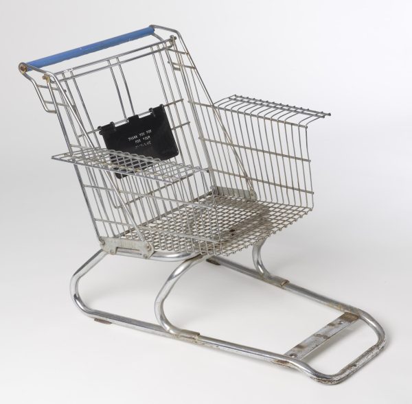A metal grocery cart without wheels has been modified for use as an arm chair.