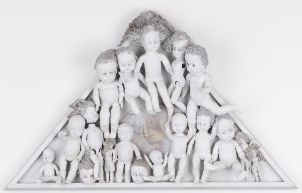 Play dolls in various sizes painted white and organized in a white triangle