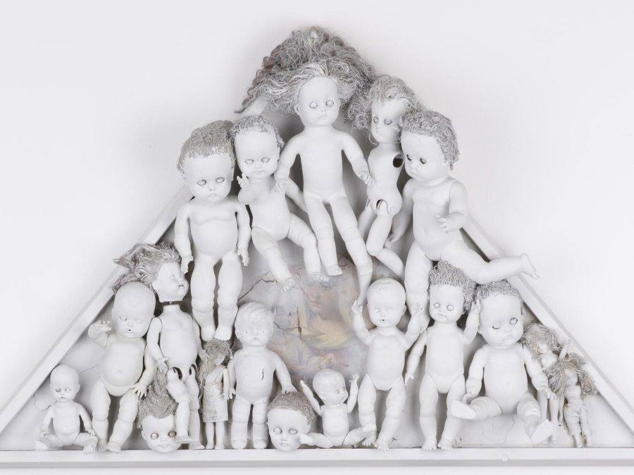 Play dolls in various sizes painted white and organized in a white triangle