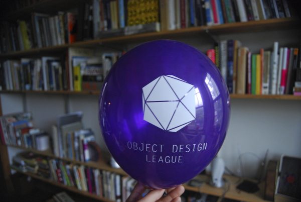 A photograph shows a purple ballon with a geometric shape printed in white and white text 