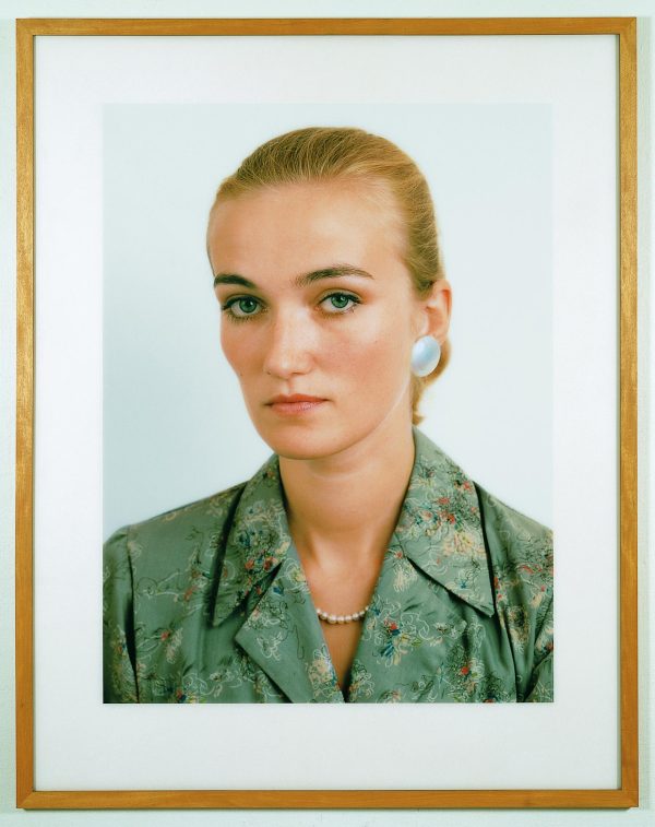 Framed portrait of a female-presenting person with light skin that looks directly into the camera with a slight frown