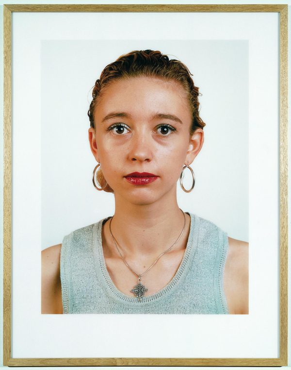 A frontal portrait features a person wearing red lipstick and a grey tank top.