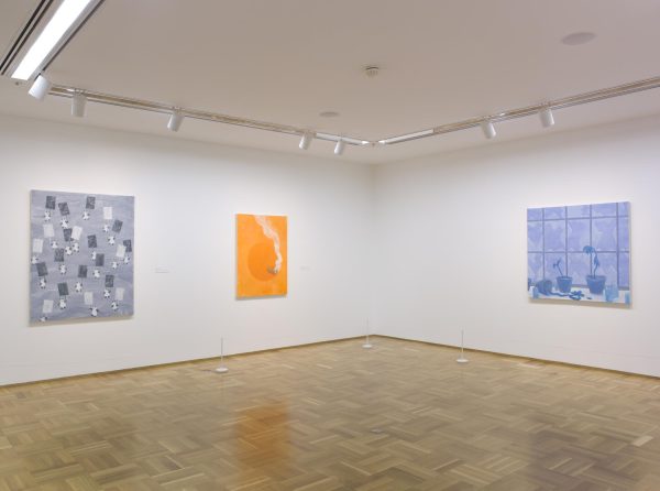 View of two walls in a gallery; two paintings hang on the left wall, one painting hangs on the right