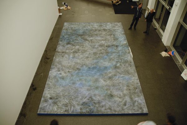 A large abstract painting on the floor as viewed from one story up