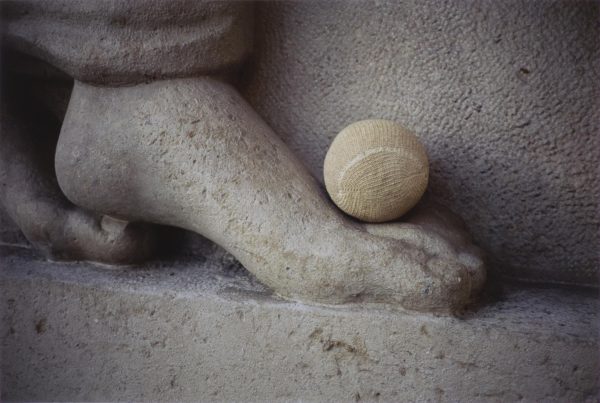 Close up of a tennis ball on the top portion of a relief sculpture's foot
