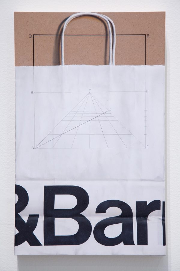 A Crate and Barrel bag with a piece of brown construction paper in it featuring a drawing of a square in it that is just visible through bag
