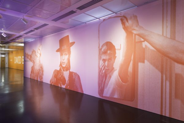 Various images of David Bowie printed in orange on a pink wall