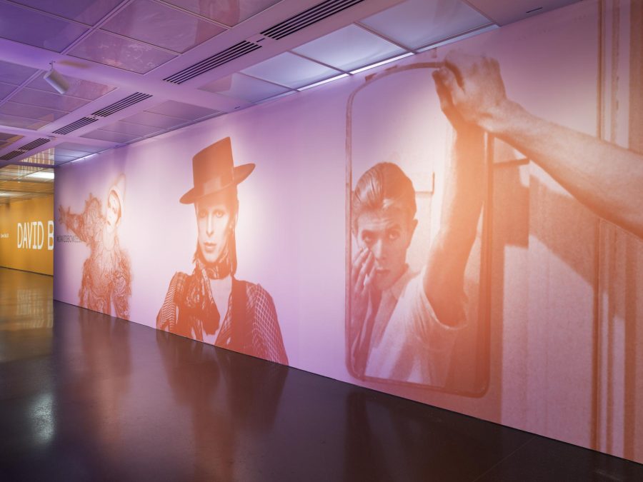 Various images of David Bowie printed in orange on a pink wall