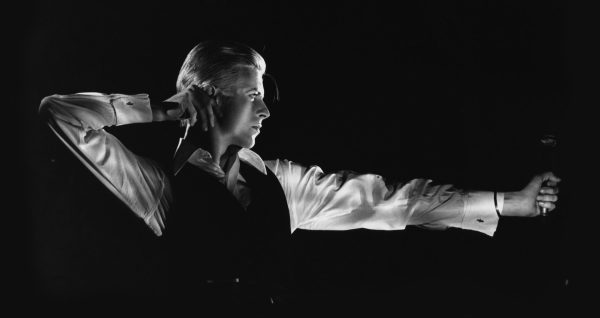 Black and white photo of David Bowie posing in an archer position