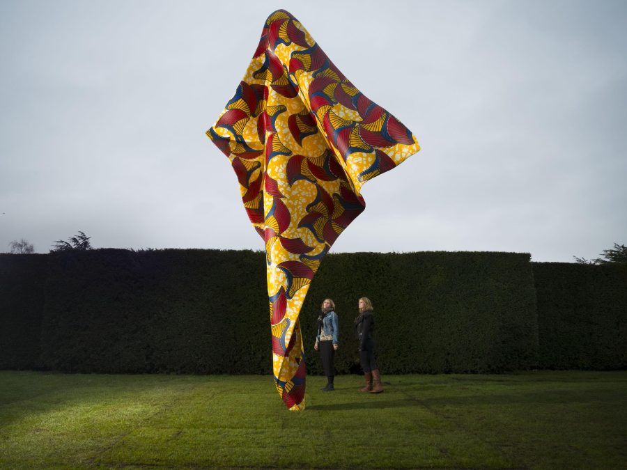 A giant sculpture resembling tussled fabric stands upright in a manicured lawn
