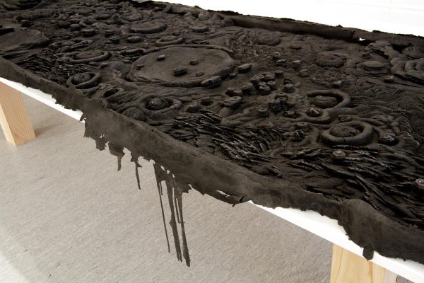 A black substance covered in pocks slightly spills over a white table